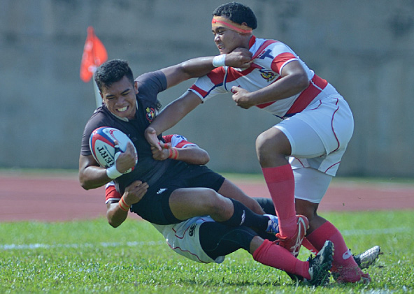 Pergerakkan Flyhalf Kolej Melayu Kuala Kangsar Mohamad Faris bin Pead(tengah) berjaya dikekang oleh pemain Sekolah Tuanku Abdul Rahman Ipoh semasa perlawanan akhir Malaysian Super Six Schools Rugby Fifteens yang diadakan di Stadium Inspen Kampus 2, Bangi.- FOTO: Sukandaily